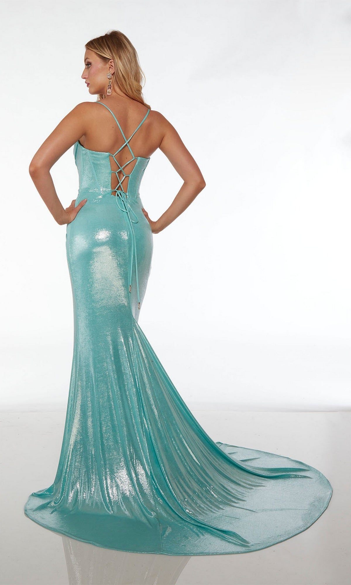 Woman in an aqua Alyce Strappy-Back Long Metallic Prom Dress 61490 with thin straps and a lace-up back, standing on a white background facing away from the camera. This shimmering mermaid gown exudes modern elegance.